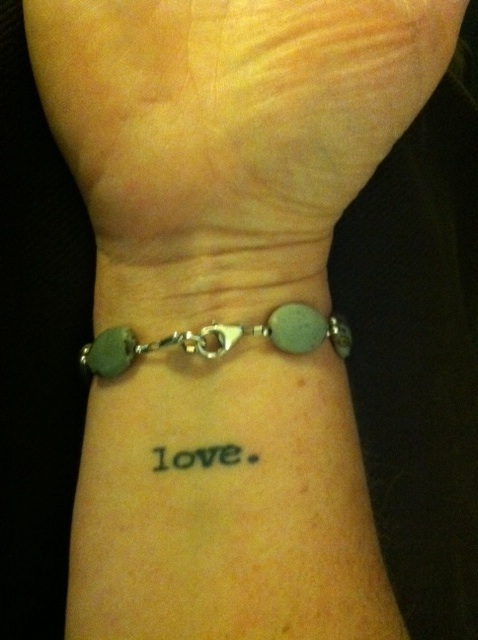 a tattoo on a woman's wrist that says "love."